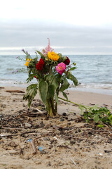 Porzucony bukiet kwiatów na plaży wbity w piach - obrazy, fototapety, plakaty
