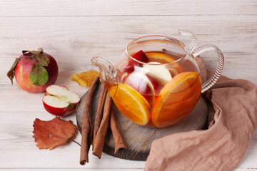 tea with fruits and berries in a glass teapot on a white wooden background