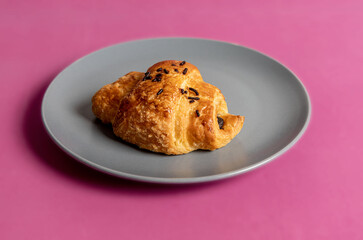 Fresh croissant isolated on pink background, close up, copy space