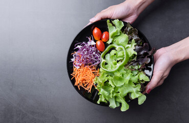 salad with fresh tomato, carrot, lettuce on black background. Healthy vegan food. Top view. Banner
