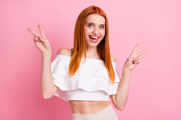 Portrait of attractive cheerful girlish red-haired girl showing double v-sign having fun isolated over pink pastel color background