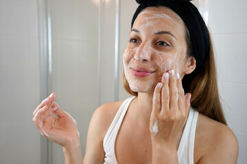 Young Skin Care Routine. Girl washing face foaming soap scrubbing skin. Face wash exfoliation scrub...