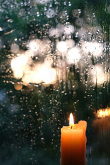 burning candle and glass with rain drops texture. rainy summer or autumn day. melancholic atmosphere image
