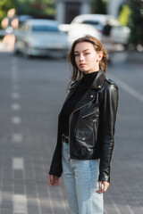 pretty young woman in black leather jacket standing outside