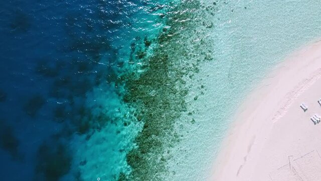 Bird's-eye view of a tropical beach. Top view of the blue beach at sunset. Beautiful beach with white sand at sunset. A bird's-eye view of a tropical beach, sea waves smoothly roll over a beautiful co