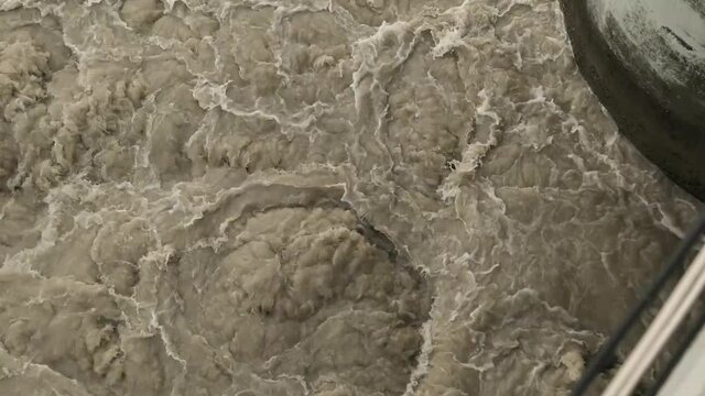 Water discharge at the city dam. Stormy streams of muddy water.