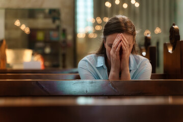 Woman is sitting in a church and praying.