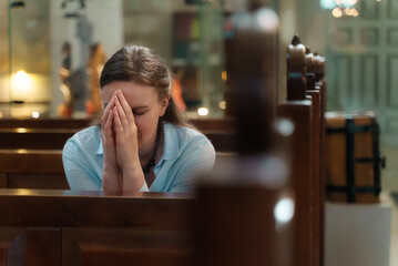 Woman is sitting in a church and praying.