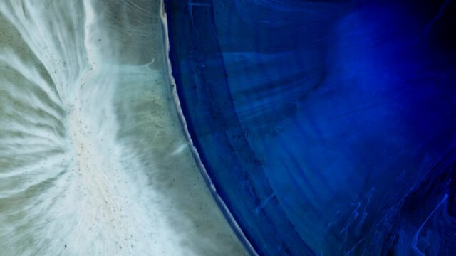 Blue, black spots are blurred on a light background. Liquid art.