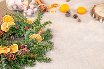 Rustic Christmas table decor, with natural spruce wreath, dried oranges, pine cones, tangerines and sweets