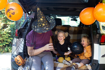 Naklejka premium Father two kids celebrating Halloween in car trunk. Autumn holiday