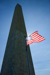 Sun shines through a U.S. flag at the Washington Monument on the National Mall in Washington, DC.