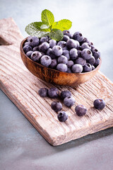 Bowl of fresh blueberries on rustic wooden board. Organic food blueberries and mint leaf for healthy lifestyle.