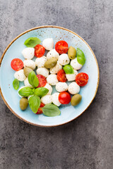 Delicious caprese salad with ripe cherry tomatoes and mini mozzarella cheese balls with fresh basil leaves.