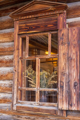 Wooden window of an old village Russian house with dried herbs and flowers behind it.