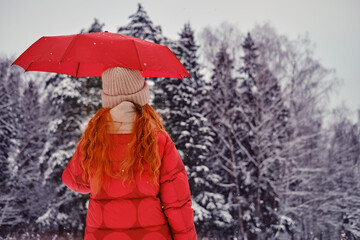 A happy woman walks with a red umbrella in her hands, a winter park with snow-covered trees