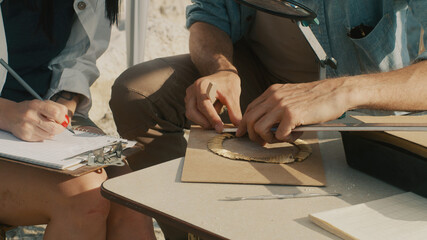 Fototapeta na wymiar Crop archaeologist measuring golden necklace