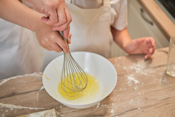 Mother and son cooking apple pie in the home kitchen. A woman and a boy in chef hats and aprons cook with pastries