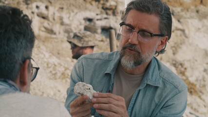 Mature archaeologist discussing fossil with colleague