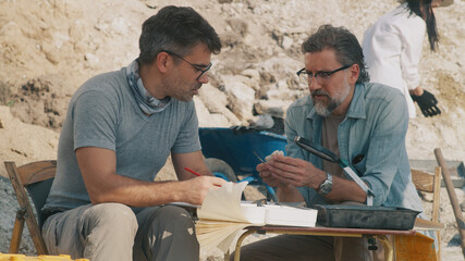 Male archaeologists analyzing findings during expedition