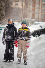 A boy in a ski suit on a snow mountain with a sled. The child is riding a sledge scooter . Active games on the street. Healthy lifestyle