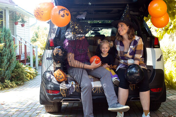 Family celebrating Halloween car trunk. Having fun together. Autumn