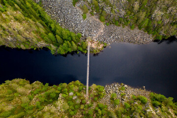 Aerial view of a suspension bridge crossing a canyon lake in a forest. Julma-Ölkky in Hossa National Park, Finland.	