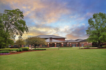Generic brick university building with beautiful landscaping and large field at sunset