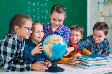 Students look at the globe in the classroom. - Powered by Adobe