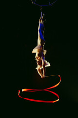 An aerial gymnast shows a performance with a ribbon in the circus arena. © davit85