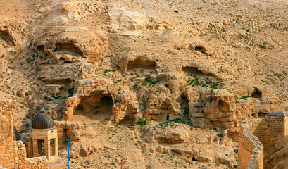 Orthodox Monastery of St. Sava the Blessed. Dome, cross, wall of the monastery. Mountains with caves of hermit monks and gorges The bottom of the stream Kidron. Jewish desert. Palestine, Israel.