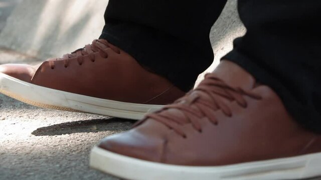 Photo of two legs with brown sneakers and black pants