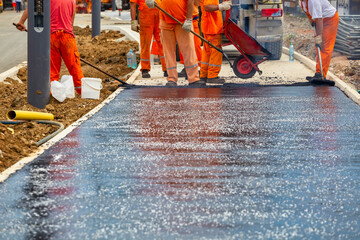 Workers melting and placing asphalt pavement