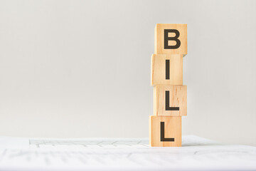 word BILL with wood building blocks, light gray background. document with numbers on background, business concept. space for text in left. front view.