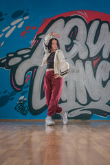 Attractive young woman doing breakdance move over graffiti background