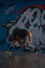 African American hip hop dancer (breakdancer) performing over graffiti background in dark silhouette exposure.