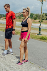 Full-length view of sportsman and sportswoman standing in front of the stairs in the park before running.