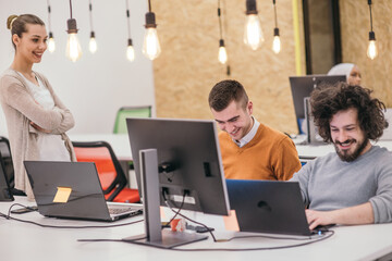 Coworkers, employees working and discussing a project they are preparing while typing on a laptop and looking at pc, computer.