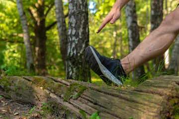 A young enduring athletic athlete is doing stretching in the forest outdoors, around the forest, oak trees. athlete forest, athletic person male, park outside. Summer body cross, runners stretches