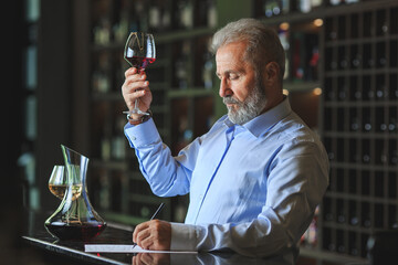 A senior sommelier is tasting red wine.
