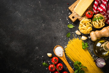 Italian food background on black. Raw Pasta, fresh tomatoes, olive oil, spices and basil. Top view...