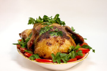 festive dish baked duck with a crispy crust garnished with slices of tomatoes and herbs on a large plate close-up on a white background