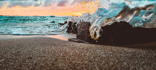 Rough water at shore with breakwater and a beautiful sunset in the horizon - obrazy, fototapety, plakaty