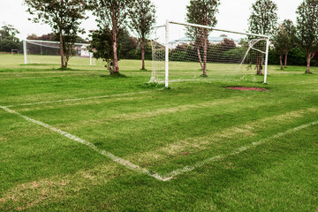 Fototapeta premium White metal soccer or football goal post and freshly cut training pitch. Cloudy sky. Simple sport background. Nobody. Cut green grass on a field.