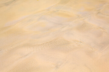 areia coberta por um fio de água translúcida e com ondas formadas pelo vento