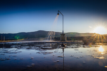Public shower in the open space in wilderness on the island of Iceland on a sunny summer evening. Reflection on the ground.