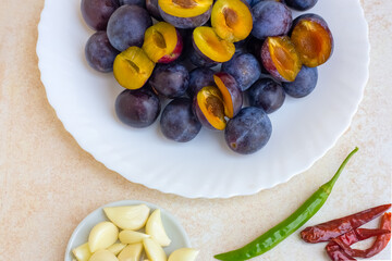 A set of products for the preparation of spicy fruit Georgian sauce tkemale. Prunes in a plate, garlic and peppers nearby