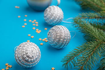Christmas or New Year composition. Decorations, silver balls, fir and spruce branches, on a blue background. Side view, close up.