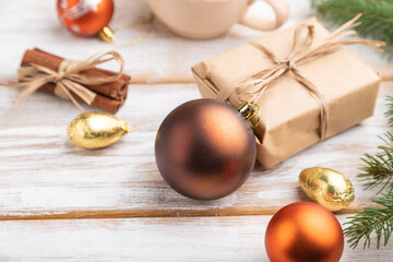 Christmas or New Year composition. Decorations, box, balls, fir and spruce branches, cup of coffee, on a white wooden background. Side view.