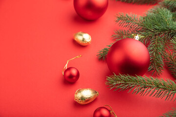Christmas or New Year composition. Decorations, red balls, fir and spruce branches, on a red background. Side view, copy space, selective focus.